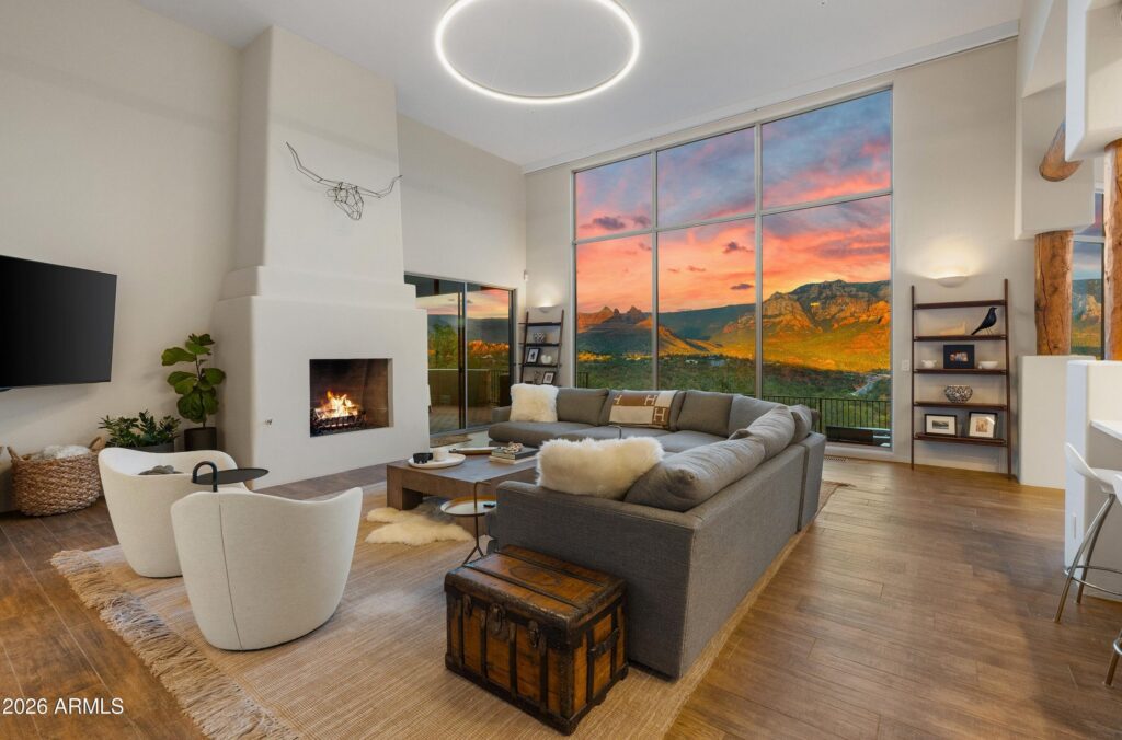 Staged Sedona living room with floor-to-ceiling windows framing red rock views at sunset