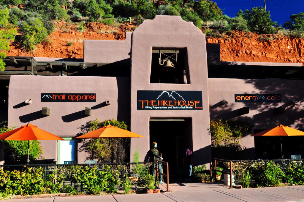 The Hike House storefront on Gallery Row in Sedona with red rocks rising behind it